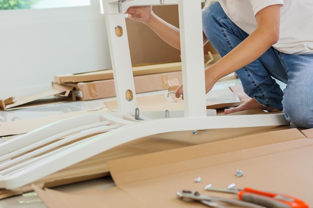 Homme assemblant des meubles de chaise blanche à la maison