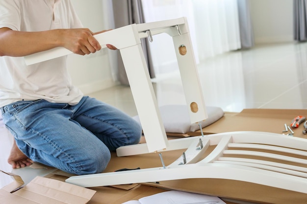 Homme assemblant des meubles de chaise blanche à la maison