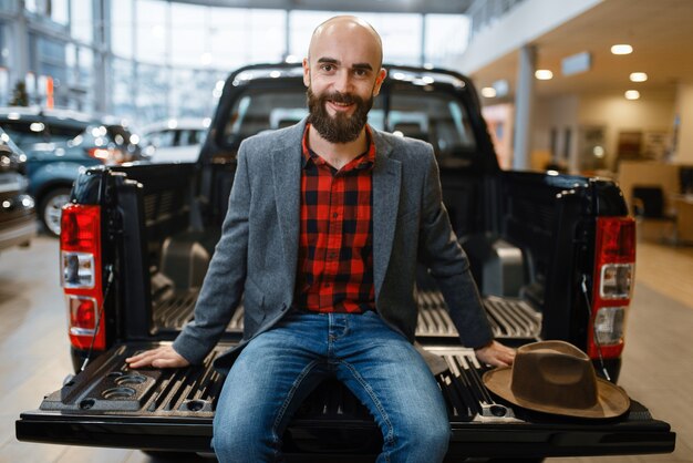 Homme Assis à L'arrière D'une Nouvelle Camionnette Chez Un Concessionnaire Automobile. Client Dans La Salle D'exposition De Véhicules, Personne De Sexe Masculin Achetant Des Transports, Entreprise De Concessionnaire Automobile