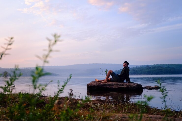 Photo un homme assis au bord du lac sur un rocher