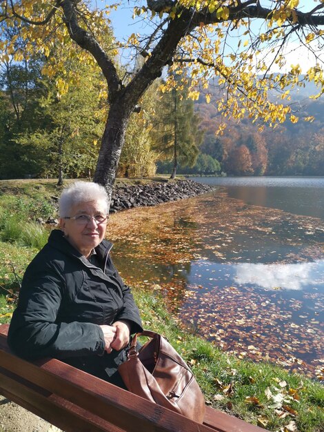 Photo un homme assis au bord d'un lac en automne