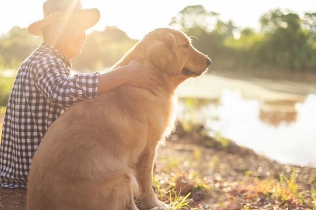 Homme assis au bord de la rivière avec un Golden Retriever brun intelligent au matin