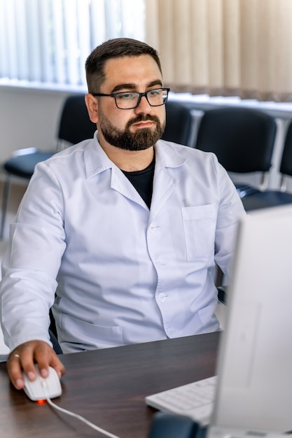 Homme assis au bureau. Docteur en gommage au bureau près de l'ordinateur. Bureau à l'hôpital.