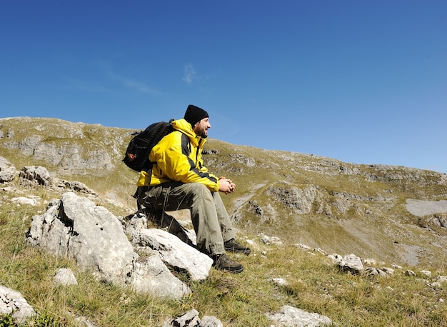 Homme assis au sommet de la montagne