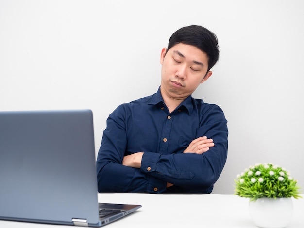 Homme assis les bras croisés sur son lieu de travail dormant avec un ordinateur portable sur la table