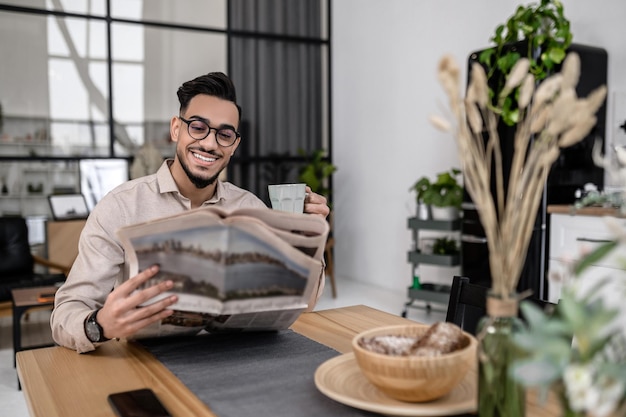 Homme assis avec un café lisant le journal