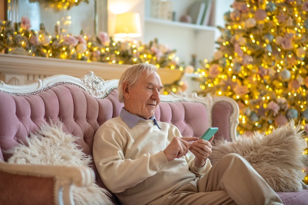 homme assis sur un canapé à l'aide de téléphone