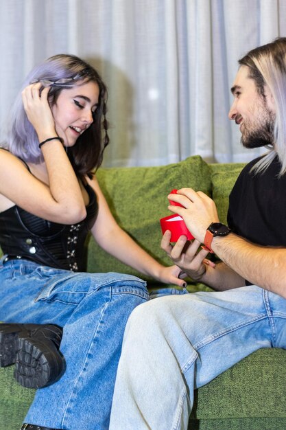 Homme assis sur le canapé faisant sa demande en mariage à sa petite amie Jeune homme assis sur le canapé faisant sa demande en mariage à sa petite amie