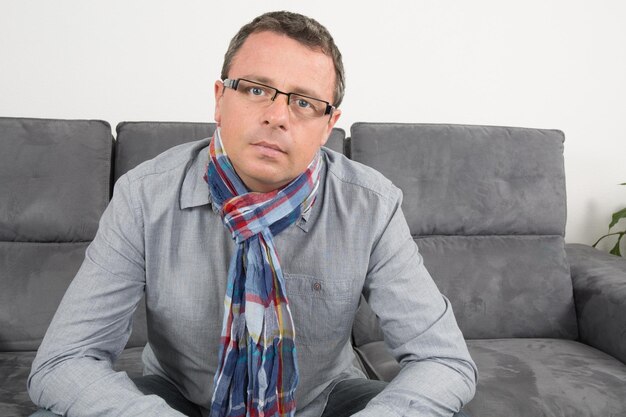 Homme assis sur un canapé à la maison à la réflexion