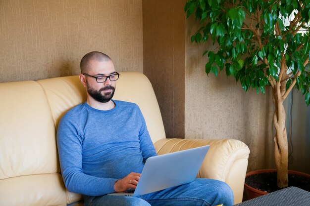 Homme assis sur le canapé avec ordinateur portable