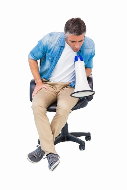 Homme assis sur une chaise de bureau parlant au mégaphone