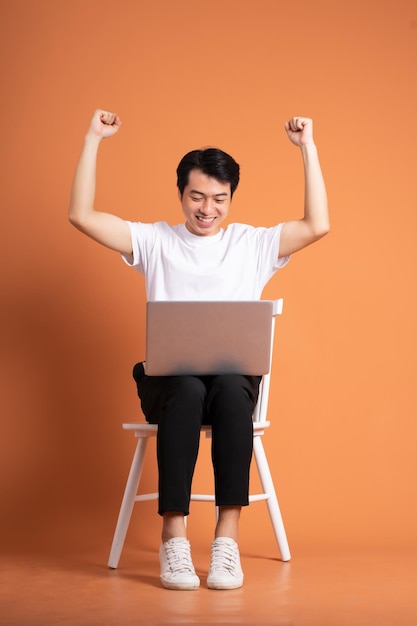 Homme assis sur une chaise isolé sur fond orange