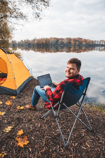 Homme assis sur une chaise près du lac d'automne