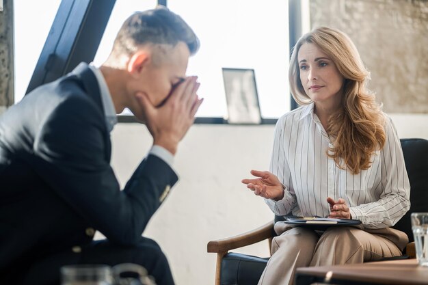 Homme assis chez le psychologue et parlant de ses problèmes