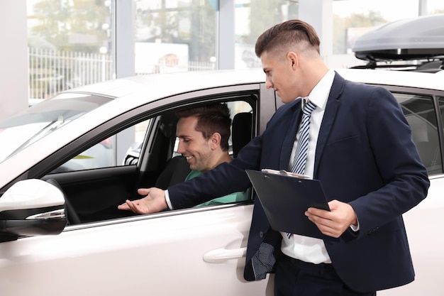 Homme assis dans le siège conducteur d'une nouvelle voiture au salon