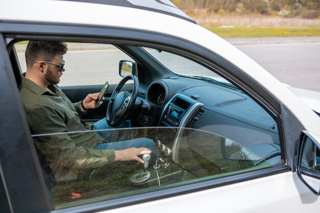 Homme assis dans une voiture à l'aide d'un mode de vie distrait par téléphone