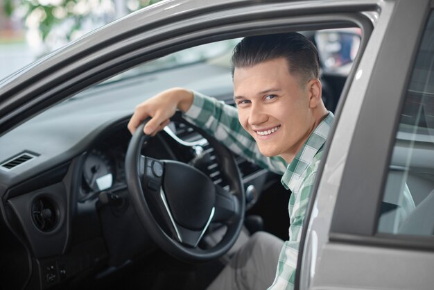 Photo homme assis dans la voiture et tenant la main sur le volant.