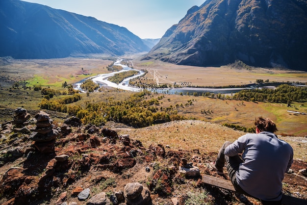 Homme assis sur le dessus avec vue sur la vallée de la rivière de montagne Russie Altaï Chulyshman River
