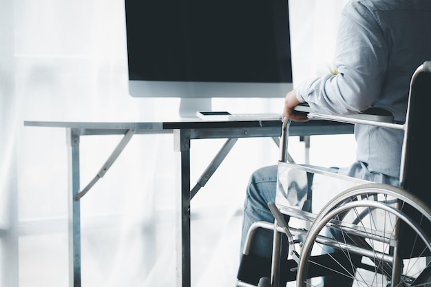 Homme assis sur un fauteuil roulant homme avec un fauteuil roulant au bureau de l'entreprise recrutant des personnes handicapées pour travailler avec une équipe dans l'entreprise et ayant une personne handicapée dans l'équipe