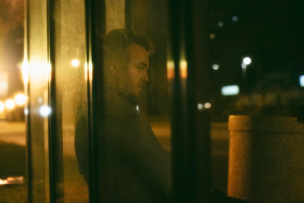 Photo homme assis à la gare routière la nuit dans la ville