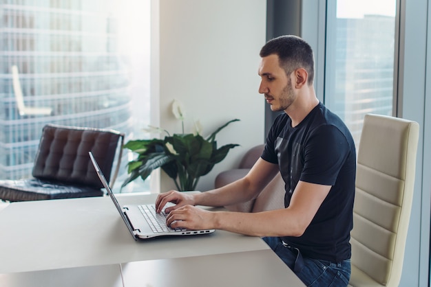 Homme assis sur le lieu de travail et utilisant un ordinateur portable.