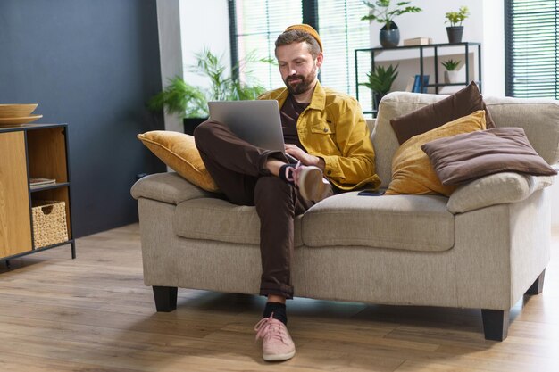 Photo homme assis à la maison absorbé par les commentaires de types d'ordinateurs portables sur les réseaux sociaux sur internet homme avec un comportement unique et excentrique lui donnant une apparence de cinglé ou de manivelle