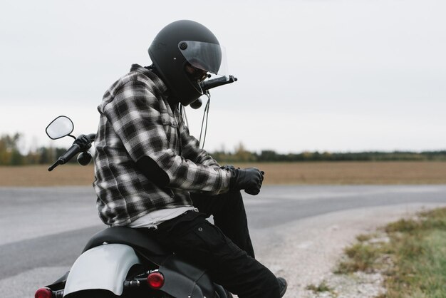 Photo un homme assis sur une moto au bord de la route contre le ciel