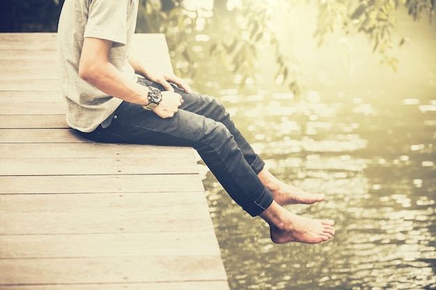 Homme assis sur le pont de bois