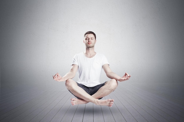 Homme assis en position de lotus de yoga avec les yeux fermés dans le studio de remise en forme Concept de relaxation et de méditation