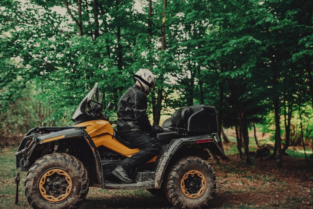 Homme assis sur un quad en forêt et se préparant à rouler