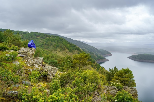 Homme assis sur un rocher en haut de la montagne un jour nuageux pluvieux