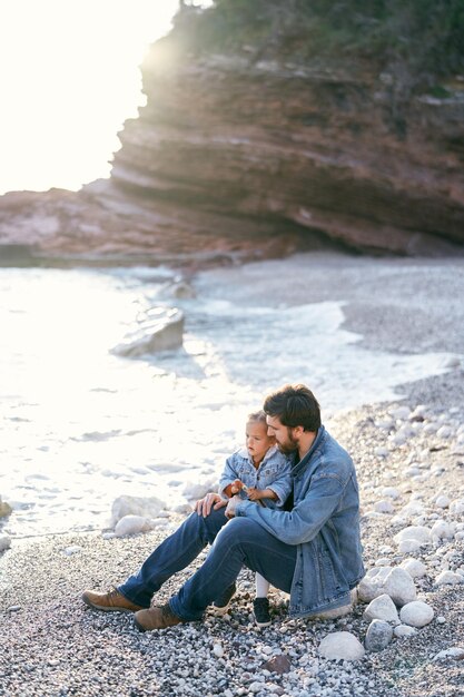 Photo un homme assis sur un rocher à la plage