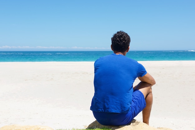 Un homme assis seul à la plage