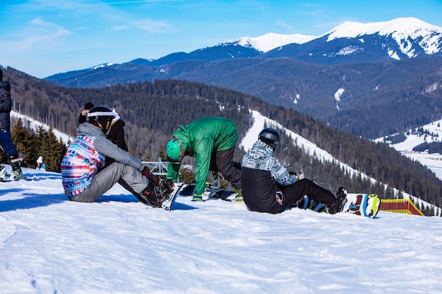 Homme assis avec snowboard au sommet de la colline avec une vue magnifique. espace de copie. journée ensoleillée