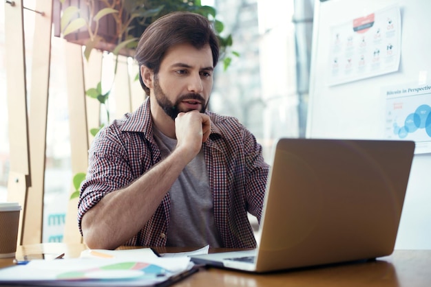 Homme assis à la table au bureau élégant créatif regardant l