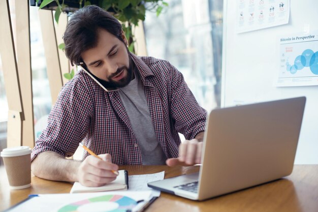 Homme assis à la table au bureau multitâche créatif et élégant