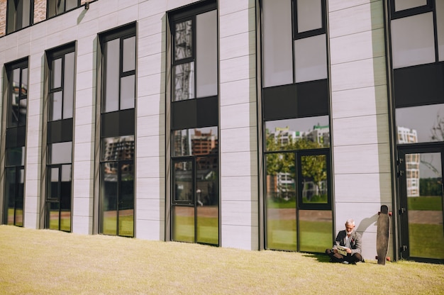 Homme assis en tailleur sur l'herbe en lisant le journal