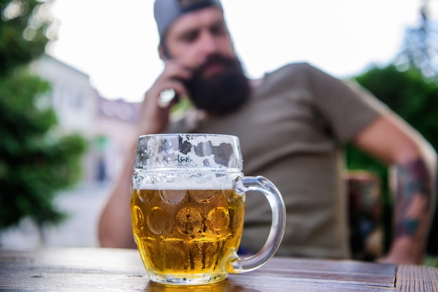 Homme assis sur la terrasse d'un café en dégustant une bière défocalisée Concept d'alcool et de bar La bière artisanale est jeune, urbaine et à la mode Culture de la bière distincte Tasse de bière fraîche fraîche sur la table en gros plan Jeune brasseur créatif