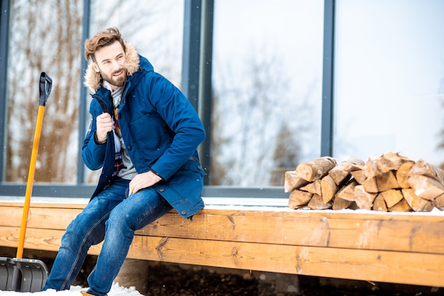 Homme assis sur la terrasse de la maison moderne pendant l'hiver