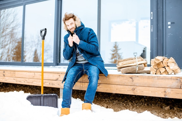 Homme assis sur la terrasse de la maison moderne pendant l'hiver