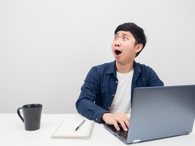 Homme assis travaillant sur le bureau se sentant étonné et regardant l'espace de copie