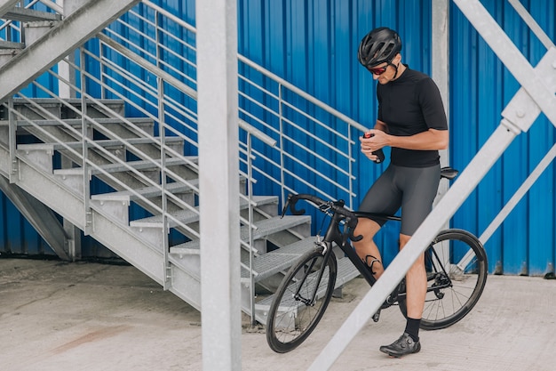 Homme assis sur le vélo avec une bouteille d'eau dans les mains