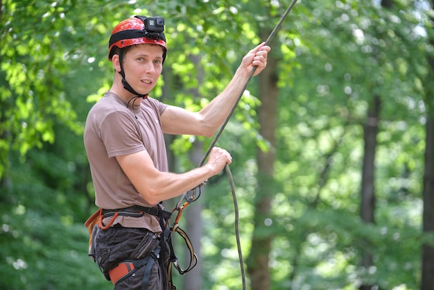 L'homme assure son grimpeur partenaire avec un dispositif d'assurage et une corde. Homme de main du grimpeur tenant un équipement pour la sécurité de l'alpinisme.