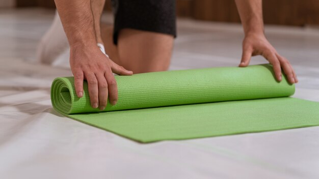 L'homme athlète déroule un tapis roulant, préparant une place pour le sport. Mec déterminé faisant de l'entraînement physique