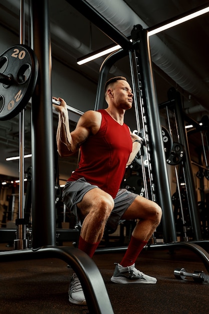 L'homme un athlète est engagé dans une salle de sport, faisant un exercice sur les muscles des bras biceps fond noir. Photo de haute qualité.