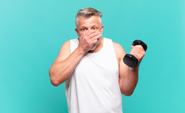 Homme athlète senior couvrant la bouche avec les mains avec une expression choquée et surprise, gardant un secret ou disant oops