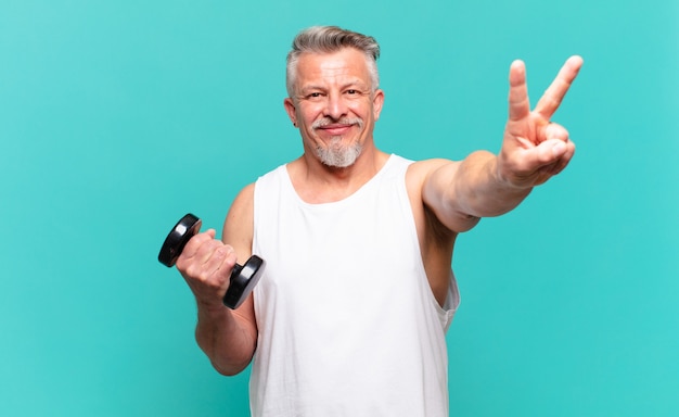 Homme athlète senior souriant et ayant l'air heureux, insouciant et positif, gesticulant la victoire ou la paix d'une main