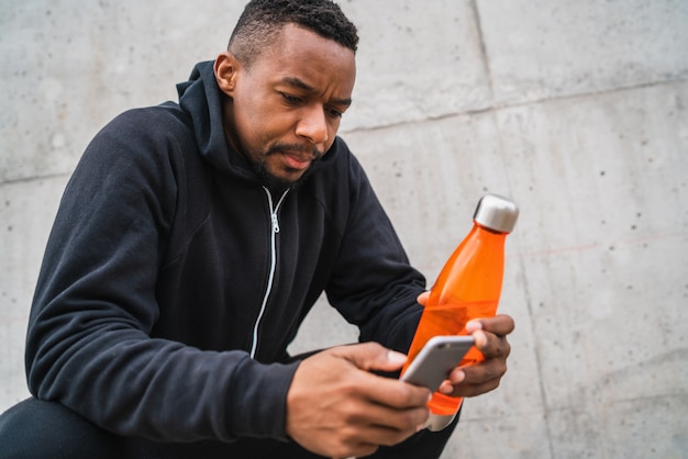 Homme athlétique à l'aide de son téléphone après la formation.