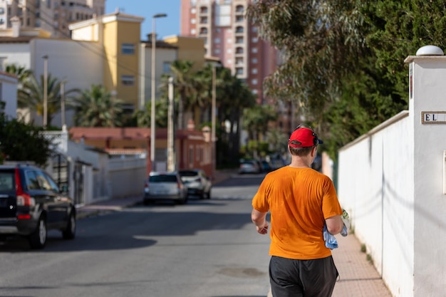 Homme athlétique courant dans le parc avec des écouteurs le jour d'été ensoleillé Mode de vie sain Les hommes adultes actifs font du jogging