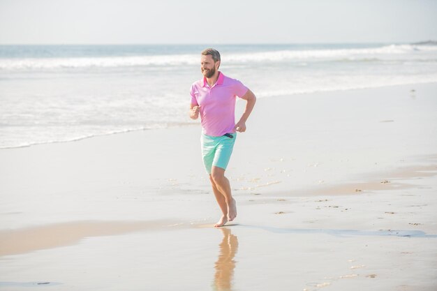 Homme athlétique courant sur la plage d'été pour l'entraînement d'été